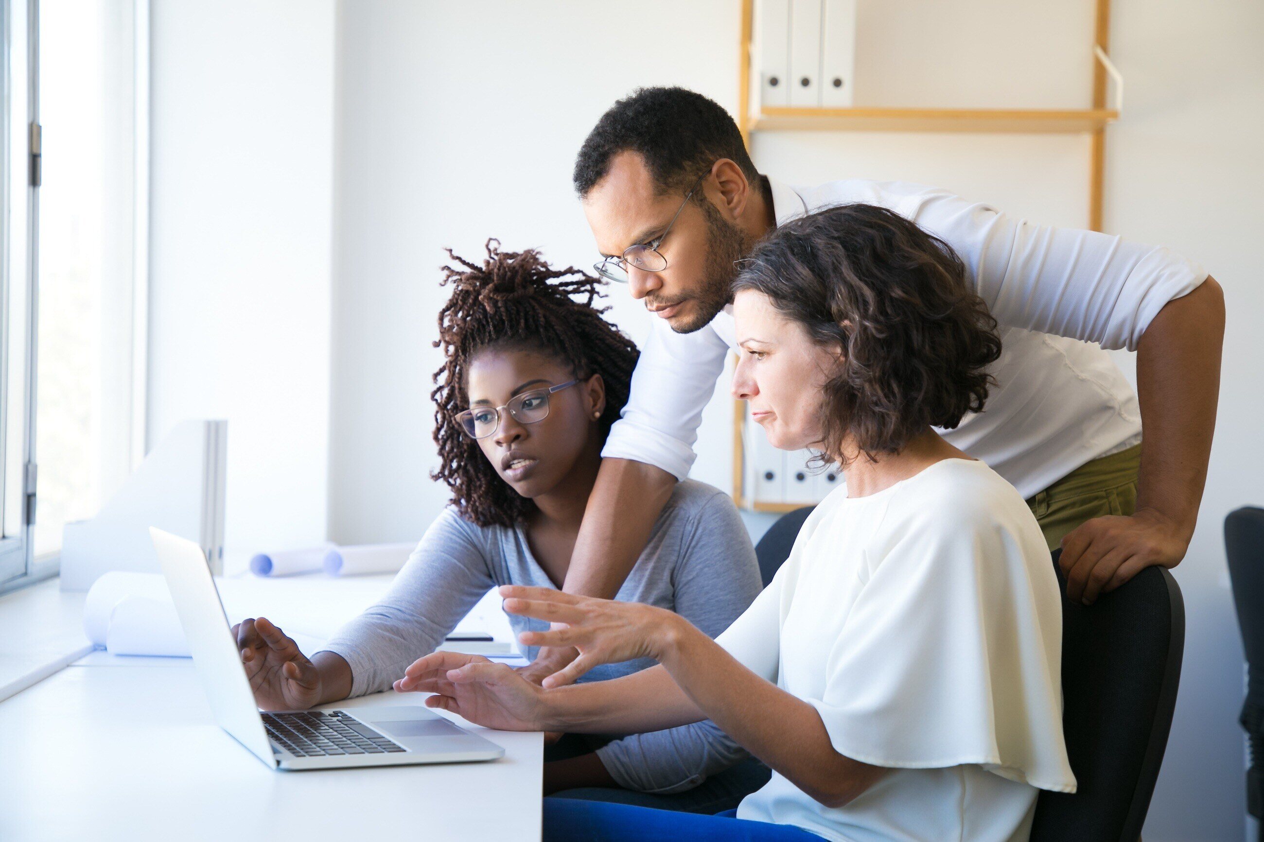 Three employees looking at data on a laptop