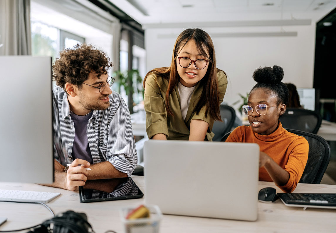 three employees looking at a laptop